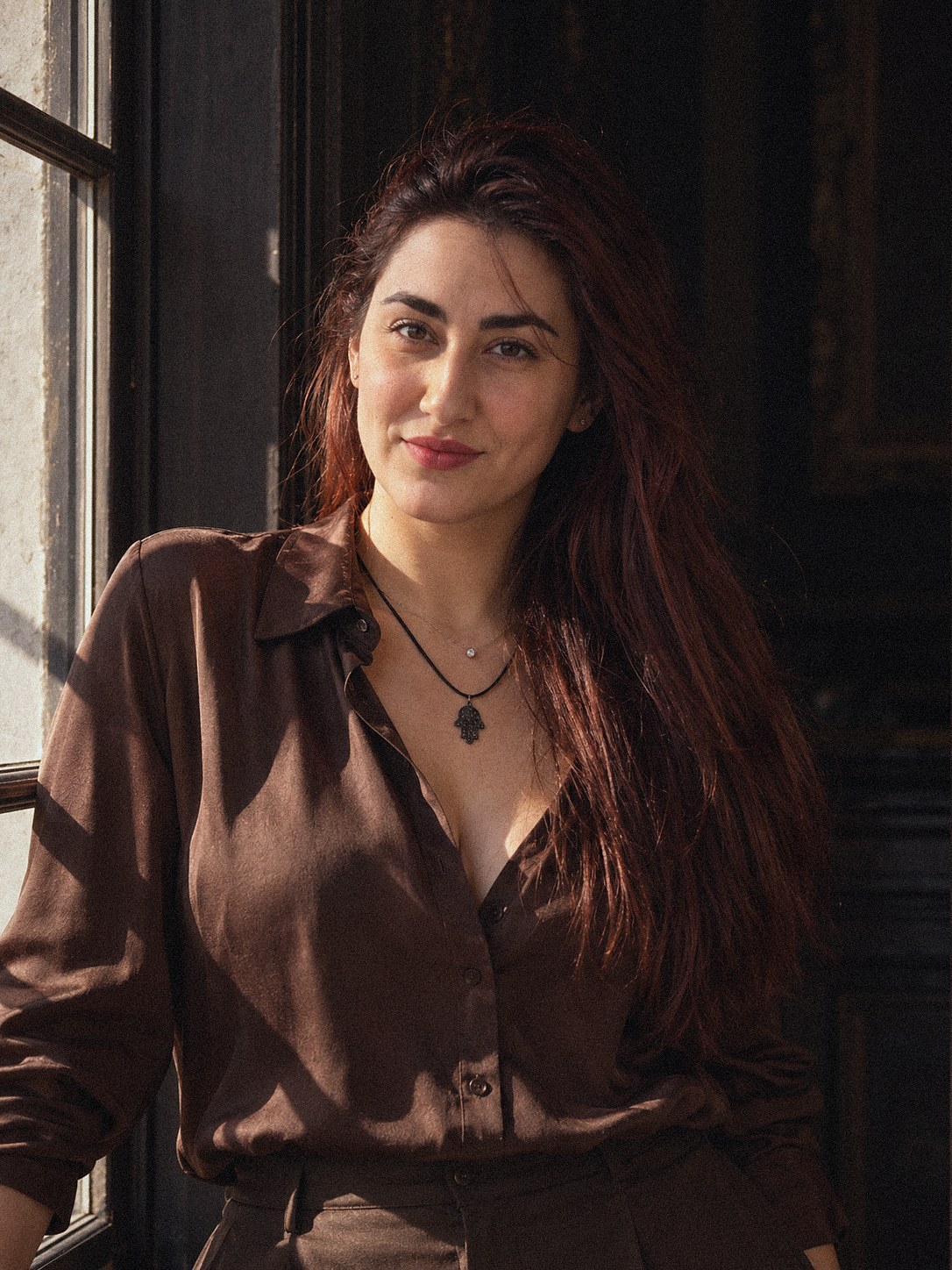 Retrato de Rachel Cossich com luz forte de janela, camisa de seda marrom